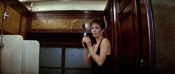 Movie still from “Nikita” (1990), directed by Luc Besson – A young woman holding a comb in a room; Medium shot, Low angle