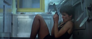 Movie still from “Nikita” (1990), directed by Luc Besson – A woman in a black dress holding a cell phone; Medium shot, Low angle