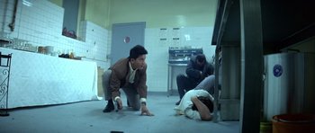 Movie still from “Nikita” (1990), directed by Luc Besson – A group of people in a room with a table and chairs; Wide shot, High angle