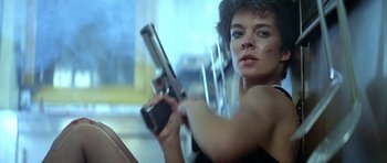 Movie still from “Nikita” (1990), directed by Luc Besson – A woman holding a gun while sitting in a car; Close Up shot, Low angle
