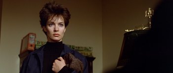 Movie still from “Nikita” (1990), directed by Luc Besson – A woman holding onto a jacket in a living room; Close Up shot, Low angle