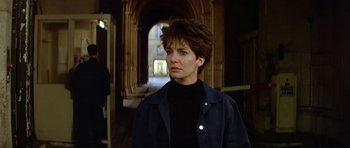 Movie still from “Nikita” (1990), directed by Luc Besson – A woman with short hair is standing in an archway; Close Up shot, Low angle