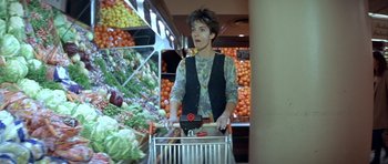 Movie still from “Nikita” (1990), directed by Luc Besson – A woman pushing a shopping cart in a grocery store; Medium shot, Low angle