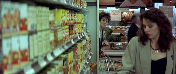 Movie still from “Nikita” (1990), directed by Luc Besson – A woman in a grocery store with a shopping cart; Medium shot, Over the shoulder angle