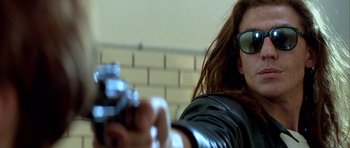 Movie still from “Nikita” (1990), directed by Luc Besson – A woman in a leather jacket is holding a gun; Close Up shot, Low angle
