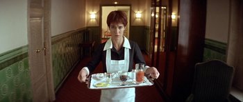 Movie still from “Nikita” (1990), directed by Luc Besson – A woman holding a tray of food in a hotel room; Medium shot, Low angle