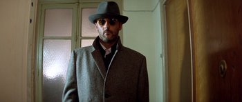 Movie still from “Nikita” (1990), directed by Luc Besson – A man wearing a hat and a coat; Close Up shot, Low angle