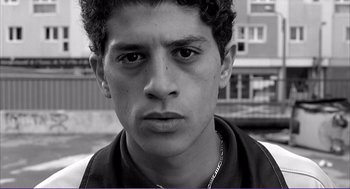 Movie still from “La haine” (1995), directed by Mathieu Kassovitz – Black and white photograph of a young man looking at the camera; Close Up shot, Low angle