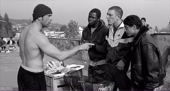 Movie still from “La haine” (1995), directed by Mathieu Kassovitz – A group of young men standing next to each other on a deck; Medium shot, Over the shoulder angle