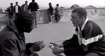 Movie still from “La haine” (1995), directed by Mathieu Kassovitz – Two young men are talking to each other; Medium shot, Over the shoulder angle