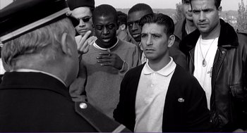 Movie still from “La haine” (1995), directed by Mathieu Kassovitz – A black and white photo of a group of people; Medium shot, Over the shoulder angle