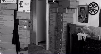 Movie still from “La haine” (1995), directed by Mathieu Kassovitz – A room filled with lots of cardboard boxes stacked on top of each other; Wide shot, High angle