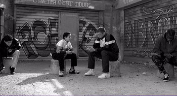 Movie still from “La haine” (1995), directed by Mathieu Kassovitz – Two young men are sitting on a bench; Wide shot, Low angle