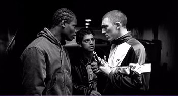 Movie still from “La haine” (1995), directed by Mathieu Kassovitz – A group of young men standing next to each other; Medium shot, Low angle