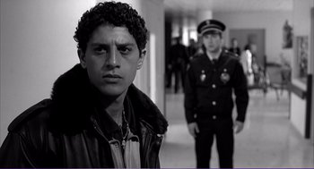 Movie still from “La haine” (1995), directed by Mathieu Kassovitz – A young man standing in front of a police officer; Close Up shot, Over the shoulder angle