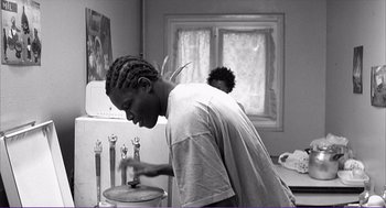 Movie still from “La haine” (1995), directed by Mathieu Kassovitz – A man in a white t - shirt is looking into a mirror; Medium shot, Low angle