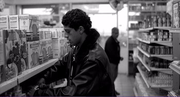 Movie still from “La haine” (1995), directed by Mathieu Kassovitz – A young man is looking at a shelf in a store; Medium shot, Low angle
