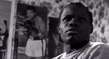 Movie still from “La haine” (1995), directed by Mathieu Kassovitz – A black and white photo of a man in front of a wall; Close Up shot, Low angle