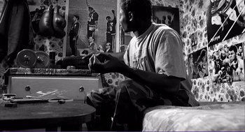 Movie still from “La haine” (1995), directed by Mathieu Kassovitz – A black and white photo of a man playing drums; Medium shot, Low angle