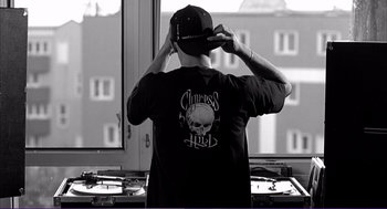 Movie still from “La haine” (1995), directed by Mathieu Kassovitz – A man in a black shirt and a hat; Medium shot, Low angle