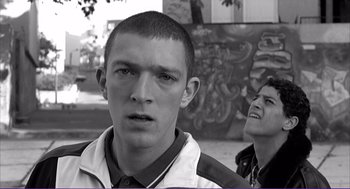 Movie still from “La haine” (1995), directed by Mathieu Kassovitz – A young man with a shaved head and a man with short hair; Close Up shot, Low angle