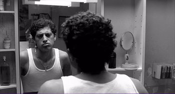 Movie still from “La haine” (1995), directed by Mathieu Kassovitz – A man looking in the mirror in front of a mirror; Close Up shot, Low angle