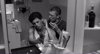 Movie still from “La haine” (1995), directed by Mathieu Kassovitz – A man and a woman in a bathroom looking at a cell phone; Medium shot, Over the shoulder angle