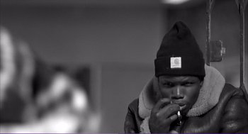 Movie still from “La haine” (1995), directed by Mathieu Kassovitz – A black and white photo of a man smoking a cigarette; Close Up shot, Low angle