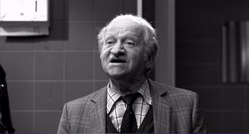 Movie still from “La haine” (1995), directed by Mathieu Kassovitz – An old man in a suit and tie looking up; Close Up shot, Low angle