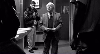 Movie still from “La haine” (1995), directed by Mathieu Kassovitz – A man standing in a bathroom next to another man; Medium shot, Over the shoulder angle