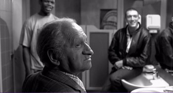 Movie still from “La haine” (1995), directed by Mathieu Kassovitz – An old man with a beard and mustache and two other men in the background; Medium shot, Over the shoulder angle