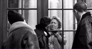 Movie still from “La haine” (1995), directed by Mathieu Kassovitz – An older woman and a younger man are looking at each other through a window; Medium shot, Over the shoulder angle