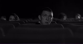 Movie still from “La haine” (1995), directed by Mathieu Kassovitz – A man sitting in an empty movie theater; Medium shot, Low angle