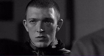 Movie still from “La haine” (1995), directed by Mathieu Kassovitz – Black and white photograph of a young man in a leather jacket; Close Up shot, Low angle