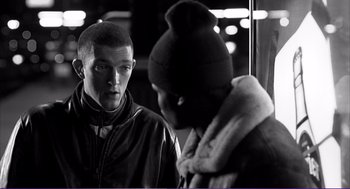 Movie still from “La haine” (1995), directed by Mathieu Kassovitz – Two young men standing next to each other on a street; Medium shot, Over the shoulder angle
