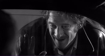 Movie still from “La haine” (1995), directed by Mathieu Kassovitz – A black - and - white photo of a man looking out a car window; Close Up shot, Low angle