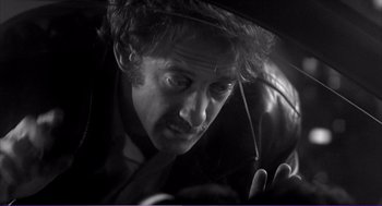 Movie still from “La haine” (1995), directed by Mathieu Kassovitz – A black and white photo of a man holding an umbrella; Close Up shot, Over the shoulder angle