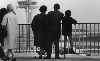 Movie still from “La Jetée” (1962), directed by Chris Marker – A group of people standing next to a railing; Wide shot, Low angle