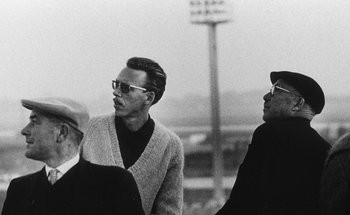 Movie still from “La Jetée” (1962), directed by Chris Marker – A group of men standing next to each other on top of a field; Medium shot, Low angle