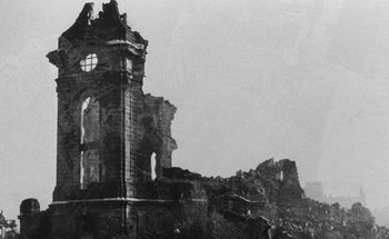 Movie still from “La Jetée” (1962), directed by Chris Marker – An image of an old building that has a clock on the side of it; Extreme Wide shot, Low angle