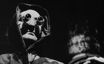 Movie still from “La Jetée” (1962), directed by Chris Marker – A man with a hooded jacket and a pair of glasses on his head; Close Up shot, Low angle