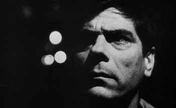 Movie still from “La Jetée” (1962), directed by Chris Marker – Black and white photograph of a man's face in the dark; Close Up shot, Low angle