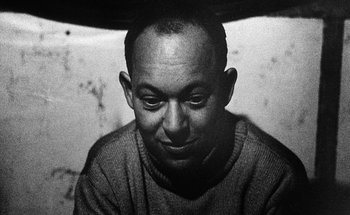Movie still from “La Jetée” (1962), directed by Chris Marker – A man in a sweater is looking at the camera; Close Up shot, Low angle