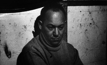 Movie still from “La Jetée” (1962), directed by Chris Marker – A man in a sweater is sitting in a room; Close Up shot, Low angle