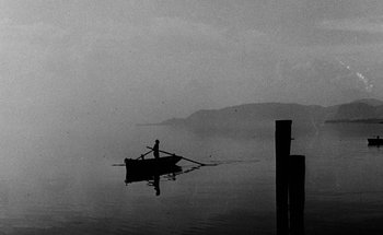 Movie still from “La Jetée” (1962), directed by Chris Marker – A man rowing a boat on a body of water; Extreme Wide shot, High angle