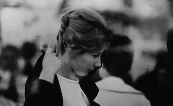 Movie still from “La Jetée” (1962), directed by Chris Marker – A black - and - white photo of a woman with her hand on her head; Close Up shot, Over the shoulder angle
