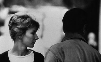 Movie still from “La Jetée” (1962), directed by Chris Marker – A woman standing next to a man on a street; Close Up shot, Over the shoulder angle