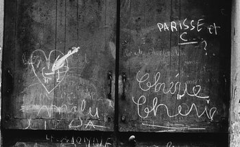 Movie still from “La Jetée” (1962), directed by Chris Marker – A black and white photo of a door with graffiti written on it; Extreme Close Up shot, Overhead angle