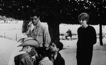 Movie still from “La Jetée” (1962), directed by Chris Marker – A black and white photo of a group of men and women; Medium shot, Over the shoulder angle