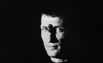 Movie still from “La Jetée” (1962), directed by Chris Marker – A black and white photo of a man's face with a gun on his forehead; Close Up shot, Low angle